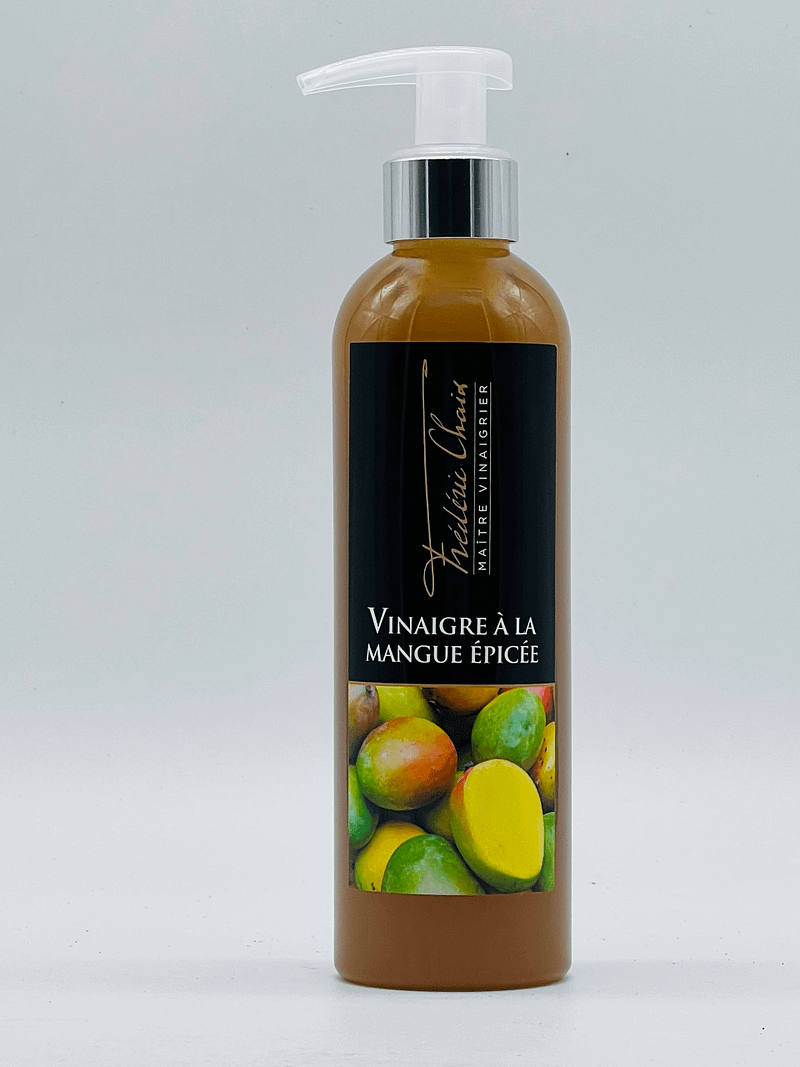 Photo du vinaigre à la mangue épicée de Frédéric Chaix, accompagné d'une salade exotique et de tranches de mangue fraîche.